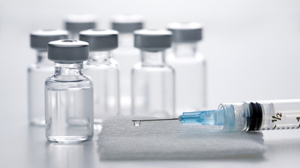 Syringe on gauze pad with vaccine bottles